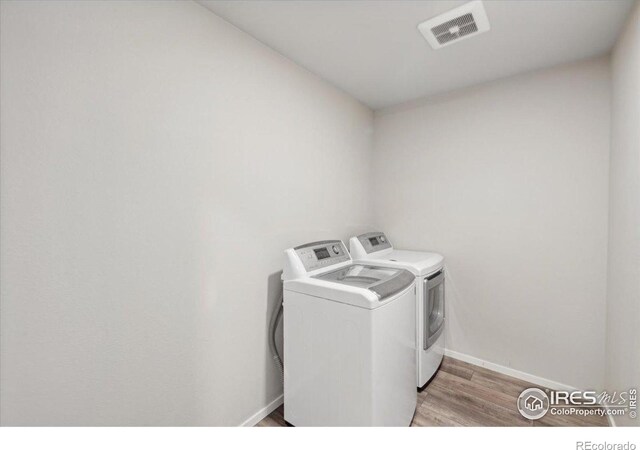 laundry area with visible vents, baseboards, laundry area, light wood-type flooring, and washing machine and dryer