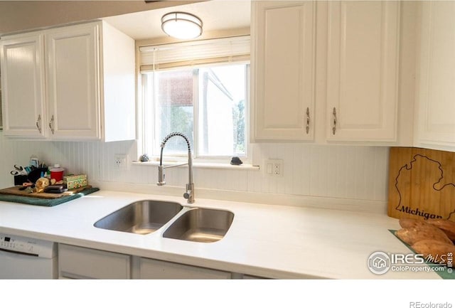 kitchen with white dishwasher, sink, and white cabinetry