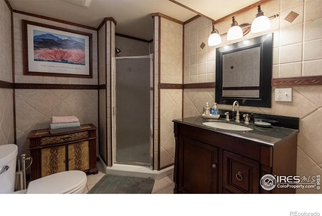 bathroom with an enclosed shower, vanity, tile walls, and toilet