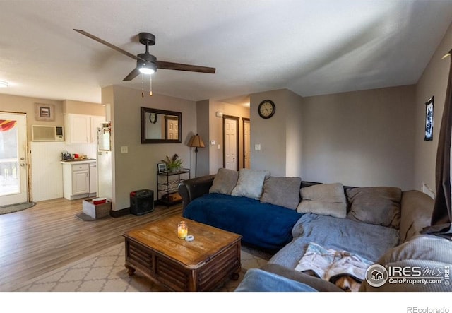 living room featuring light wood-type flooring, ceiling fan, and a wall mounted AC