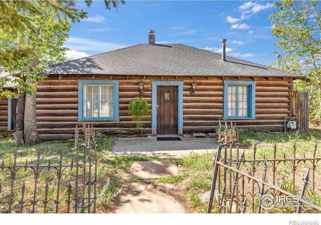 log cabin with log siding, roof with shingles, and a chimney