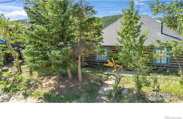 exterior space with log siding, a shingled roof, and fence