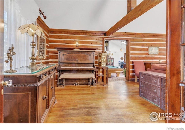 bedroom featuring beam ceiling, log walls, and light wood-style floors