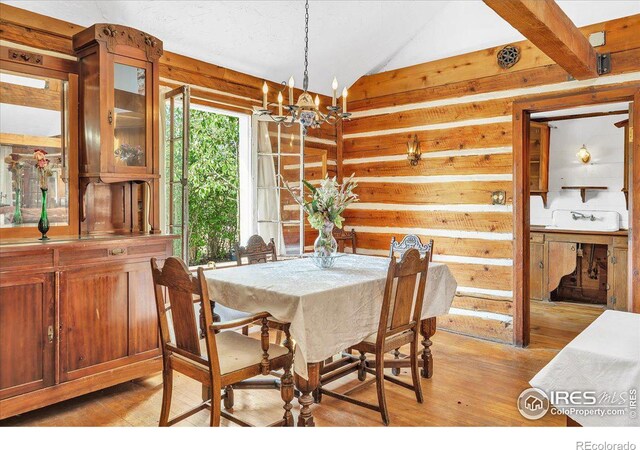 dining space featuring beamed ceiling, a chandelier, and light hardwood / wood-style floors