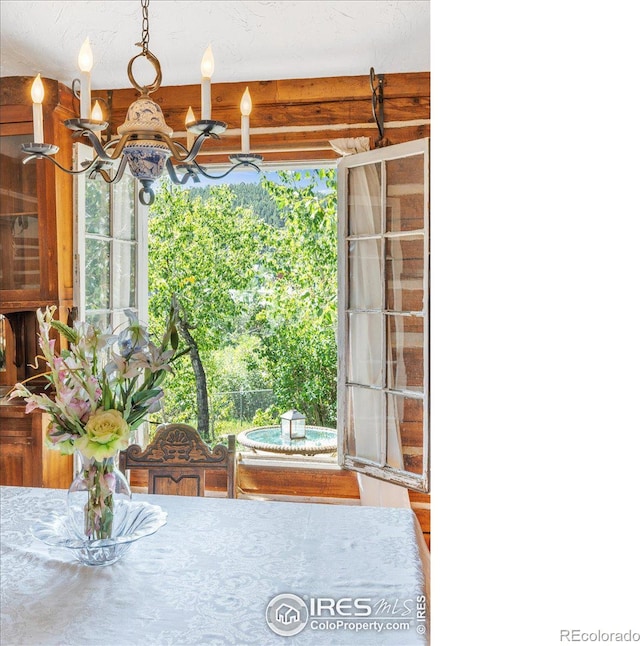 unfurnished dining area with beamed ceiling, plenty of natural light, and a notable chandelier