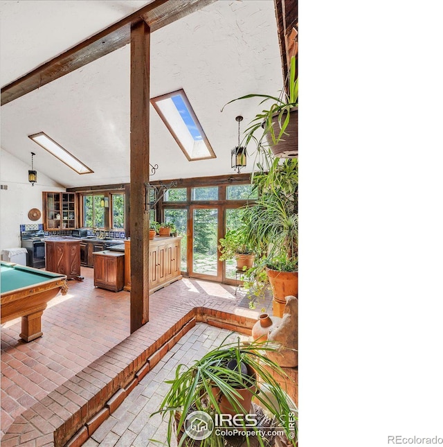 recreation room featuring lofted ceiling with skylight and brick floor