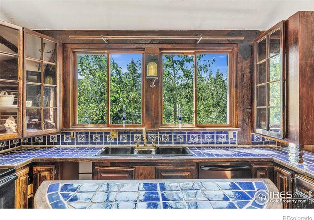 kitchen with dishwasher, tile countertops, sink, and tasteful backsplash