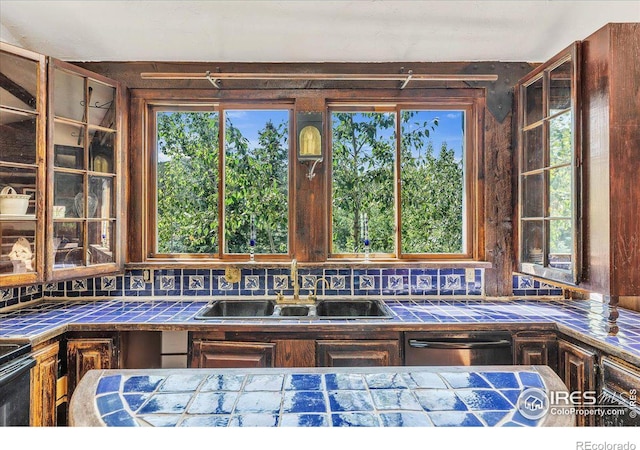 kitchen with tile countertops, black electric range oven, stainless steel dishwasher, and a sink