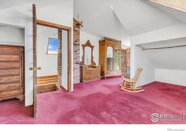 unfurnished bedroom featuring carpet floors, a textured ceiling, and vaulted ceiling