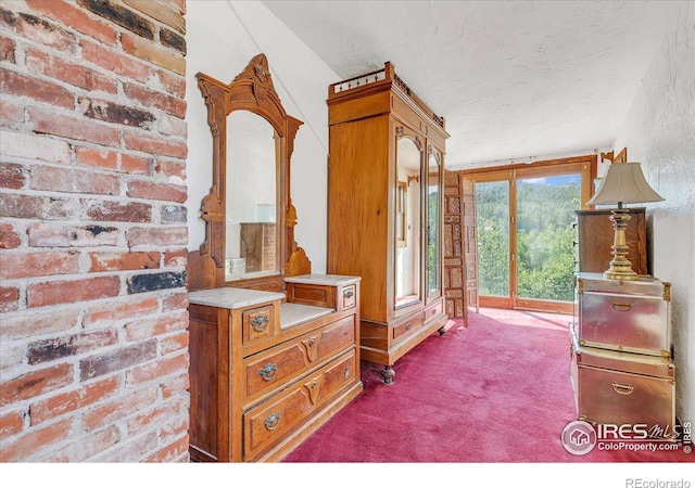 bedroom featuring access to exterior, brick wall, a textured ceiling, and carpet floors