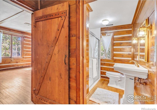 bathroom with rustic walls, visible vents, toilet, and hardwood / wood-style floors