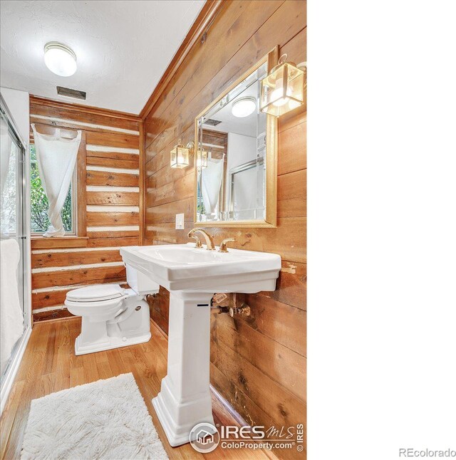 bathroom with toilet, wood-type flooring, and wooden walls