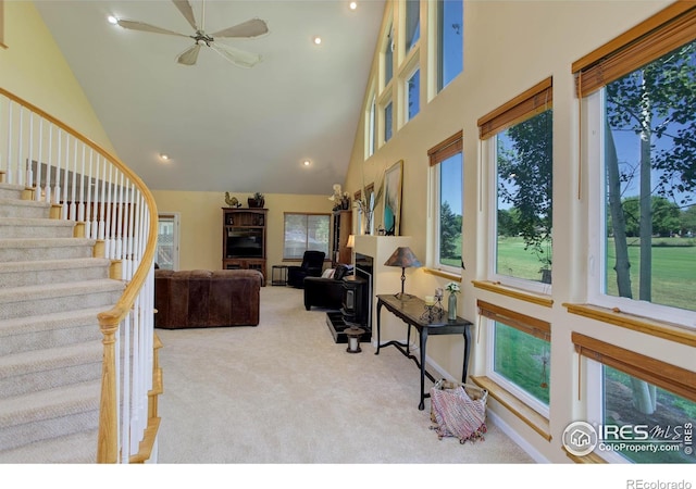 living area with ceiling fan, carpet, stairway, recessed lighting, and a towering ceiling