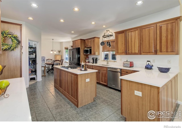 kitchen with a center island, light countertops, appliances with stainless steel finishes, brown cabinetry, and a sink