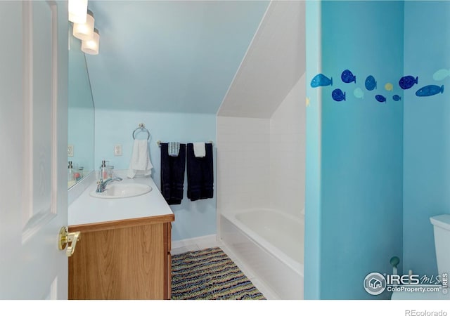 bathroom featuring tub / shower combination, toilet, vaulted ceiling, tile patterned floors, and vanity