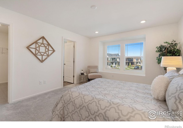 bedroom featuring a spacious closet, a closet, and light colored carpet