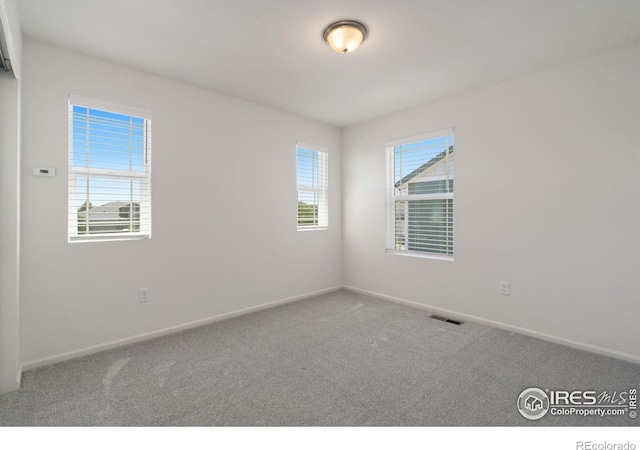 carpeted spare room featuring baseboards and visible vents