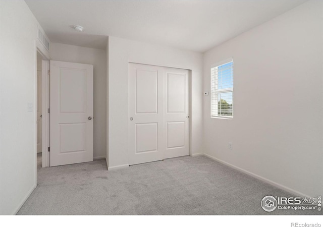 unfurnished bedroom featuring baseboards, a closet, visible vents, and carpet flooring