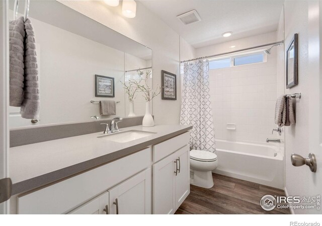 full bath featuring toilet, shower / tub combo, wood finished floors, visible vents, and vanity