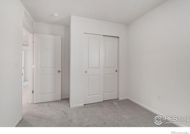 unfurnished bedroom featuring light colored carpet and a closet