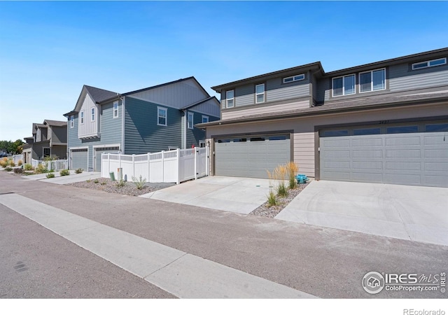 view of front of property with driveway, an attached garage, fence, and a residential view