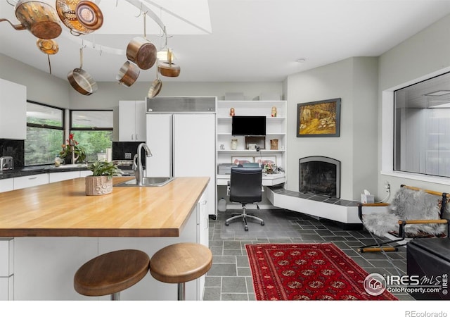 kitchen featuring white cabinets, a breakfast bar area, sink, and wood counters