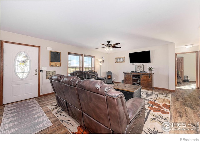 living room featuring wood finished floors, a ceiling fan, and baseboards