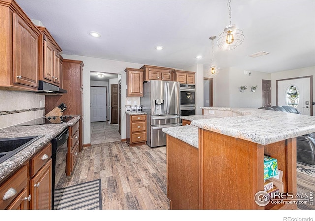 kitchen featuring decorative backsplash, a kitchen island, a breakfast bar area, ventilation hood, and black appliances