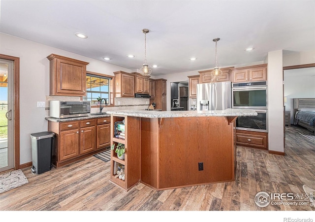 kitchen featuring a kitchen bar, a kitchen island, stainless steel appliances, and wood finished floors