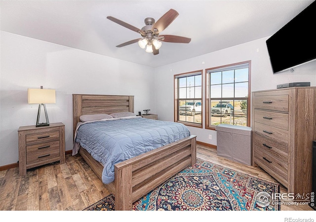 bedroom featuring light wood finished floors, baseboards, and a ceiling fan