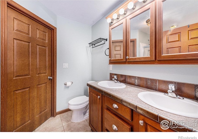 full bathroom featuring tile patterned flooring, a sink, toilet, and double vanity