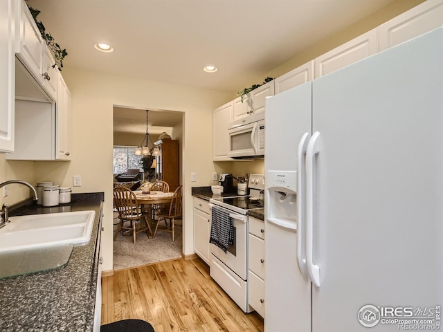 kitchen featuring dark countertops, white appliances, white cabinetry, and a sink