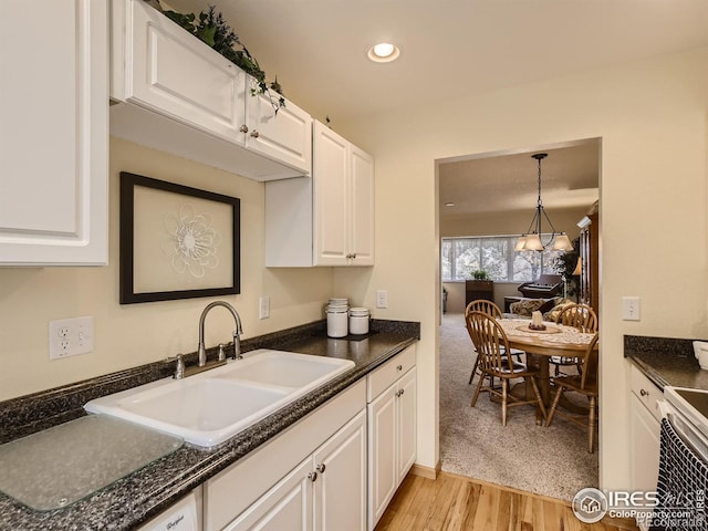 kitchen with a sink, dark countertops, recessed lighting, white cabinets, and light wood finished floors