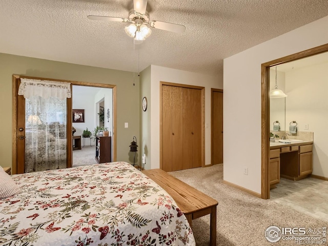 bedroom featuring two closets, light carpet, built in desk, a textured ceiling, and a sink