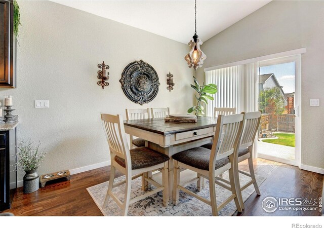 dining area featuring dark wood-type flooring and vaulted ceiling