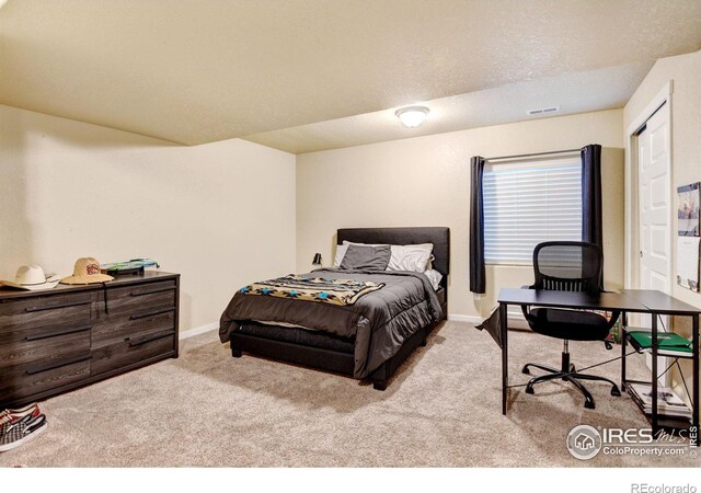 bedroom with a textured ceiling and light colored carpet