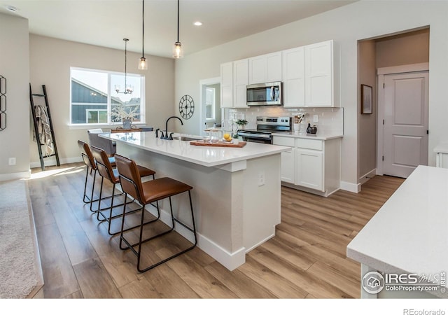 kitchen featuring a center island with sink, appliances with stainless steel finishes, sink, light wood-type flooring, and white cabinets