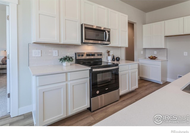 kitchen with wood-type flooring, stainless steel appliances, and white cabinets