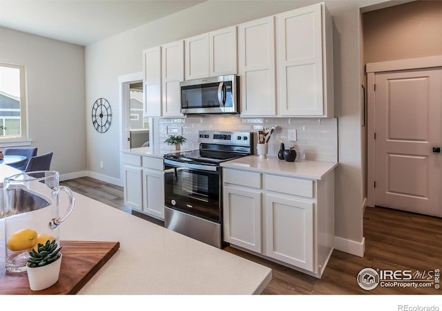 kitchen with white cabinets, appliances with stainless steel finishes, dark hardwood / wood-style flooring, and tasteful backsplash