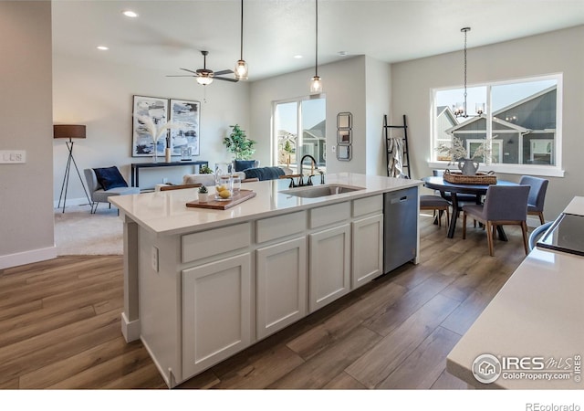 kitchen featuring ceiling fan with notable chandelier, white cabinetry, dark hardwood / wood-style flooring, sink, and a center island with sink