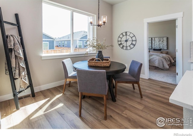 dining space featuring wood-type flooring and an inviting chandelier