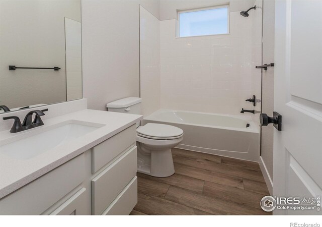 full bathroom with wood-type flooring, toilet, tiled shower / bath, and vanity