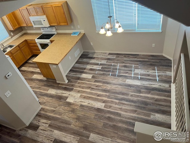 kitchen with dark hardwood / wood-style floors, sink, white appliances, and a notable chandelier