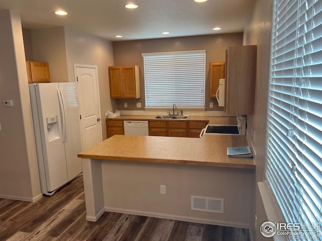 kitchen featuring white appliances, plenty of natural light, kitchen peninsula, sink, and dark hardwood / wood-style floors