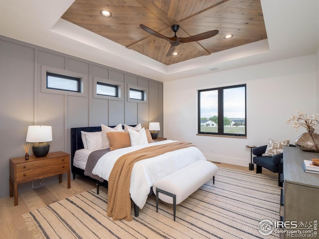 bedroom featuring light hardwood / wood-style floors, wooden ceiling, a tray ceiling, and ceiling fan