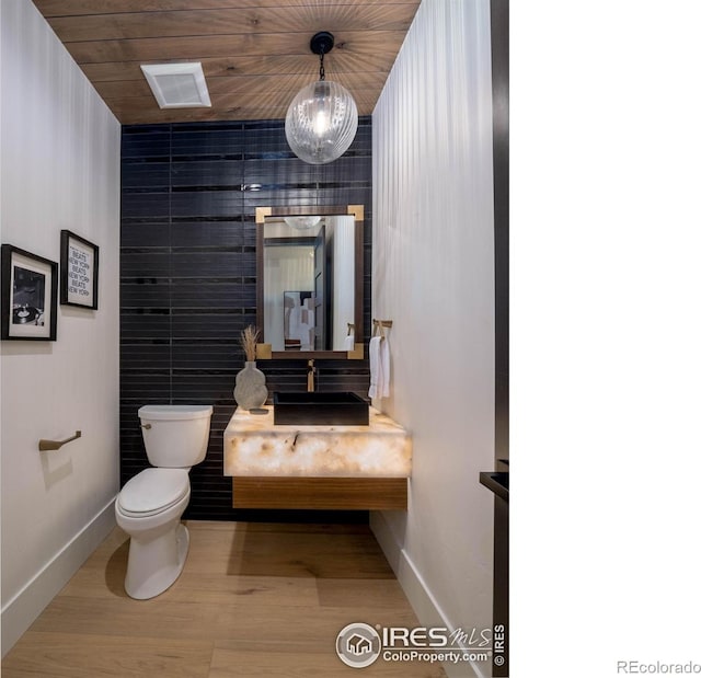 bathroom with wood ceiling, wood-type flooring, toilet, vanity, and a notable chandelier