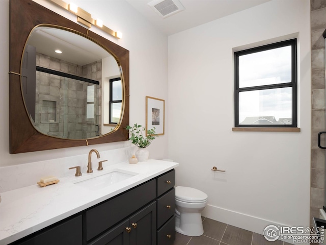 bathroom with vanity, a shower with shower door, toilet, and plenty of natural light