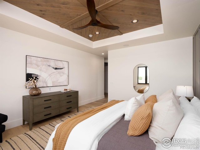 bedroom featuring wooden ceiling, a tray ceiling, and light wood-type flooring