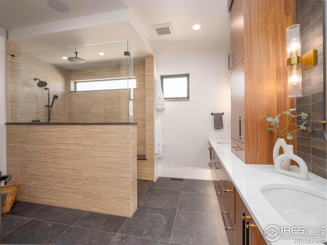 bathroom featuring vanity, a tile shower, a healthy amount of sunlight, and tile patterned flooring