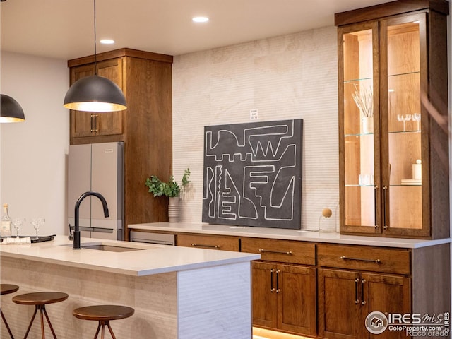 kitchen featuring sink, refrigerator, decorative light fixtures, and a breakfast bar area